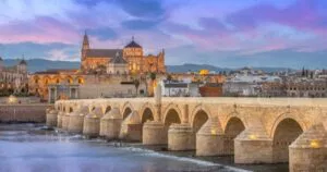 Den historiske romerske broen i Córdoba som krysser elven Guadalquivir med silhuetten til moskeen-katedralen i Córdoba i bakgrunnen, omtalt i Game of Thrones.