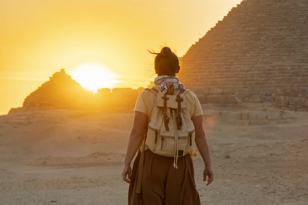Person walking towards the sunset near the Pyramids of Egypt