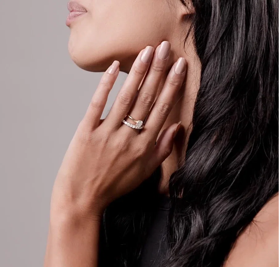 Female holding her hand up to her face showing a Diamond ring on her middle finger